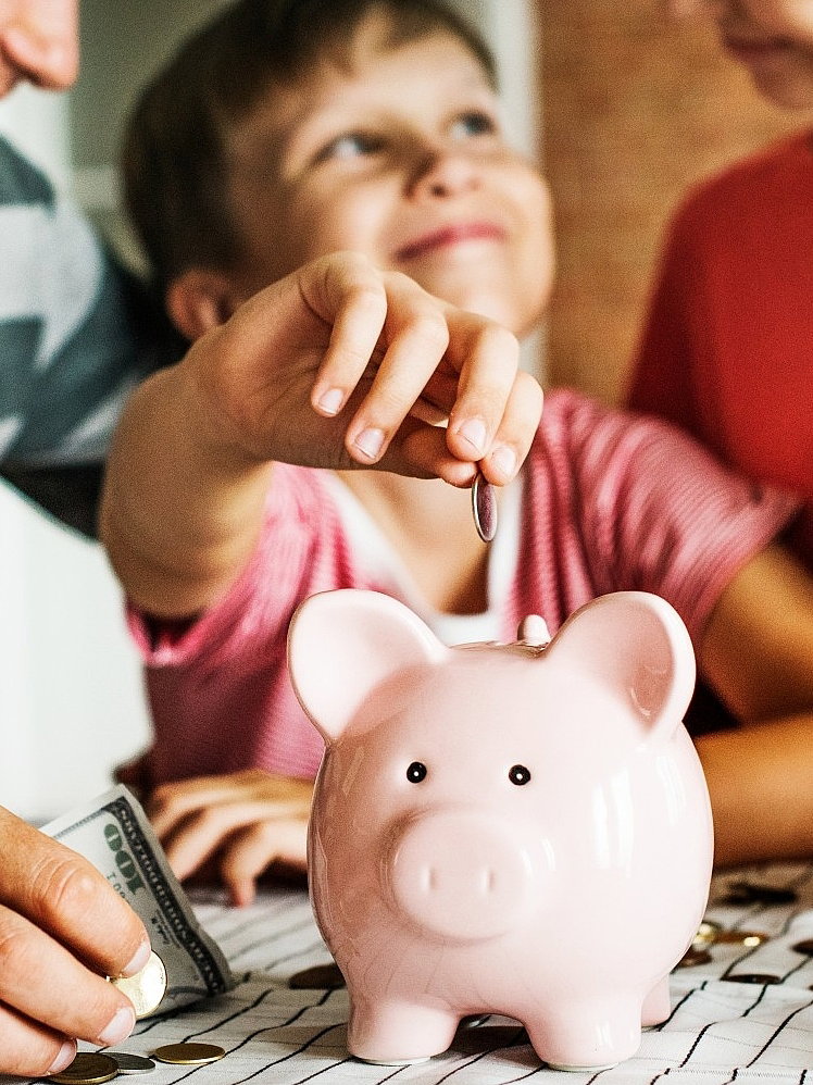 Kind zahlt in ein Sparschwein ein