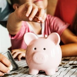 Kind zahlt in ein Sparschwein ein
