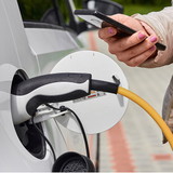 e auto lädt und person steht daneben am handy