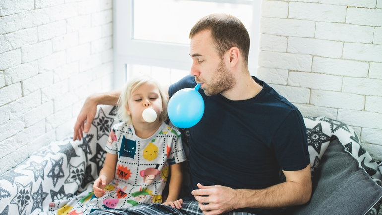 Vater pustet mit Tochter Ballons auf