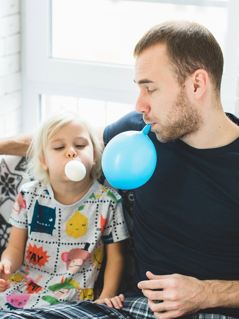 Vater pustet mit Tochter Ballons auf