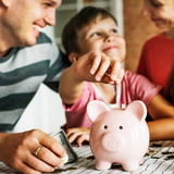 Kind packt geld in sein sparschwein mit seinen eltern